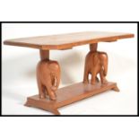 An early 20th century hardwood coffee table of rectangular form being raised on elephant carved
