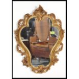 A 20th century armorial rococo shaped antique style gilt rococo wall mirror. The decorative frame