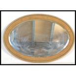 An early 20th Century Edwardian oval wall mirror having bevelled glass having a moulded frame with