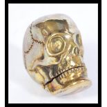 A vintage 20th century brass vesta case in the form of a skull having hinged jaw lid. Measures 4cm