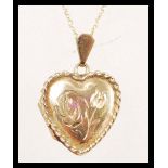 A hallmarked 9ct gold pendant necklace having a heart shaped pendant locket with floral engraving to