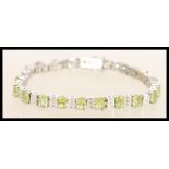 A sterling silver CZ and peridot line bracelet having alternating faceted peridots with square cut