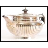 An early 20th century large hallmarked silver teapot having shaped black handle with reeded body and