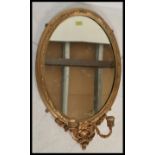 A 19th century Victorian oval gilt plaster wall / overmantel mirror being of rococo inspiration