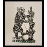 A sterling silver brooch in the form of a bear decorated with marcasites sat on an emerald set