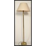 A brass Corinthian column standard lamp, with a cream lined fabric shade, on square base with paw