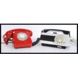 Two retro vintage 20th Century ring dial telephones - phones one in red with phone atop and the