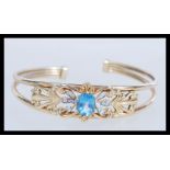 A hallmarked 9ct gold topaz and diamond cuff bangle bracelet having a large central oval mixed cut