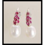 A pair of sterling silver freshwater pearl and ruby set drop earrings. Weighs 5.8 grams. 2.5cm long.