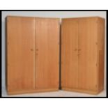 A mid century retro Meredew light oak pair of bedroom wardrobes. Each raised on plinth bases with