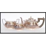 A silver plated tea service to include a tea pot with reeded decoration and ebonised wooden shaped