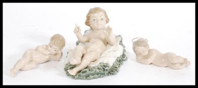 A group of three LLadro and Nao figurines to include Lladro reclined cherub with hands raised,