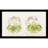A pair of 925 silver earrings prong set with oval cut peridot stones.