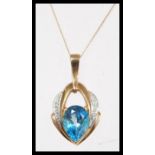 A hallmarked 9ct gold topaz and diamond pendant necklace, being set with a large pear mixed cut blue