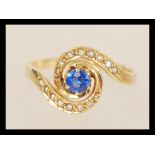 A stamped 18ct gold ring with a central prong set blue stone and seed pearl accent stones. Weight