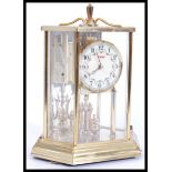 A 20th century brass anniversary clock with glass pane facia's enclosing an enamel faced dial by