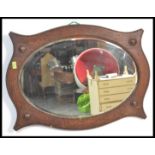A vintage 1920's Art Deco oval wall mirror having a shaped and stained dark wood frame with raised