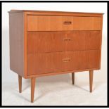 A 1970's retro Danish influence teak wood chest of drawers being raised on turned legs with two tone
