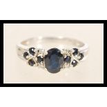 A hallmarked 9ct white gold diamond and sapphire ring having a central oval mixed cut sapphire and