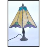 A vintage 20th century Tiffany style table lamp having a bronze effect Art Nouveau base with