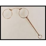 A pair of early 20th Century stamped 9ct gold lignettes / handled folding glasses with round lenses.