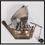 A silver / white metal model of a sailing box complete with sails moving bucket, rudder and ropes.