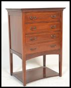 An Edwardian mahogany inlaid pedestal music cabinet having a central bank of fall front drawers with