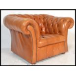 A vintage style sunburnt tan leather chesterfield armchair with a barrel rolled arms and backrest