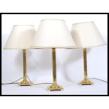 A set of three matching brass column table lamps, of Corinthian column form raised on a square