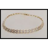 A hallmarked 9ct gold bracelet chain having a criss cross link with illusion set diamond spacers and