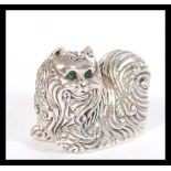 A sterling silver figurine in the form of a cat having emerald set eyes. Weighs 20.5 grams. 2cm high