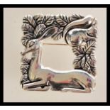 A sterling silver brooch in the manner of Georg Jensen. The open-squared brooch featuring a deer