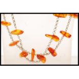 A long amber beaded necklace spaced with a silver white metal chain.