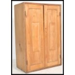 A 19th century Victorian pine school cupboard having twin fielded panel doors with inset shelves set