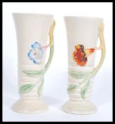 A pair of early 20th century Clarice Cliff vases of tapering cylindrical form having vine and leaf