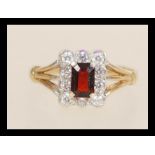 A hallmarked 9ct gold ring set with a rectangular faceted red stone with a halo of white stones.