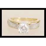 A hallmarked 9ct gold ring prong set with a brilliant cut white stone and square cut accent stones