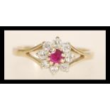 A hallmarked 9ct gold ruby and diamond ring set with a central ruby surrounded by a halo of diamonds