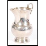 A 20th Century silver hallmarked creamer jug having a shaped handle and a stepped round base.
