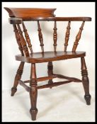A Victorian 19th century beech and elm smokers bow armchair being raised on turned legs united by