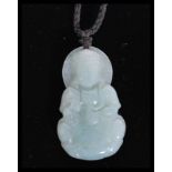 A Chinese carved jade pendant necklace in the form of a Buddha sitting in the lotus position on a