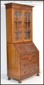 A good, circa 1920's Jacobean revival solid oak bureau bookcase cabinet being raised on bun feet