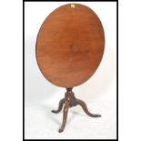 An 18th century solid mahogany tilt top wine / occasional table being raised on splayed tripod leg
