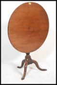 An 18th century solid mahogany tilt top wine / occasional table being raised on splayed tripod leg