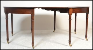 A George III mahogany crossbanded and inlaid extending d-end dining table. Raised on turned legs