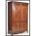 A 19th century mahogany inlaid double wardrobe being raised on French bracket kick feet with fielded