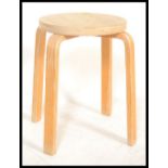 A mid century Alvar Aalto model 60 bentwood ply stool with circular seat being raised on bentwood