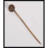 An early 20th century Edwardian 15ct gold stick pin having a flower head top with inset old cut