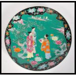 An early 20th Century Japanese Meiji period large porcelain charger having famille verte ground with