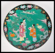 An early 20th Century Japanese Meiji period large porcelain charger having famille verte ground with